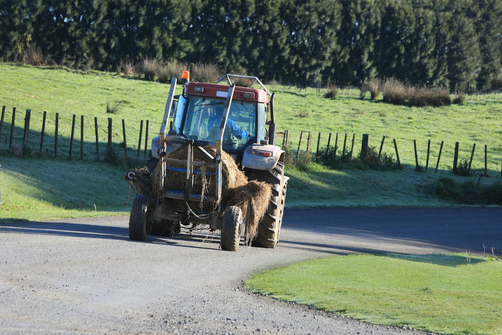 A tractor carrying hay drives along a rural road